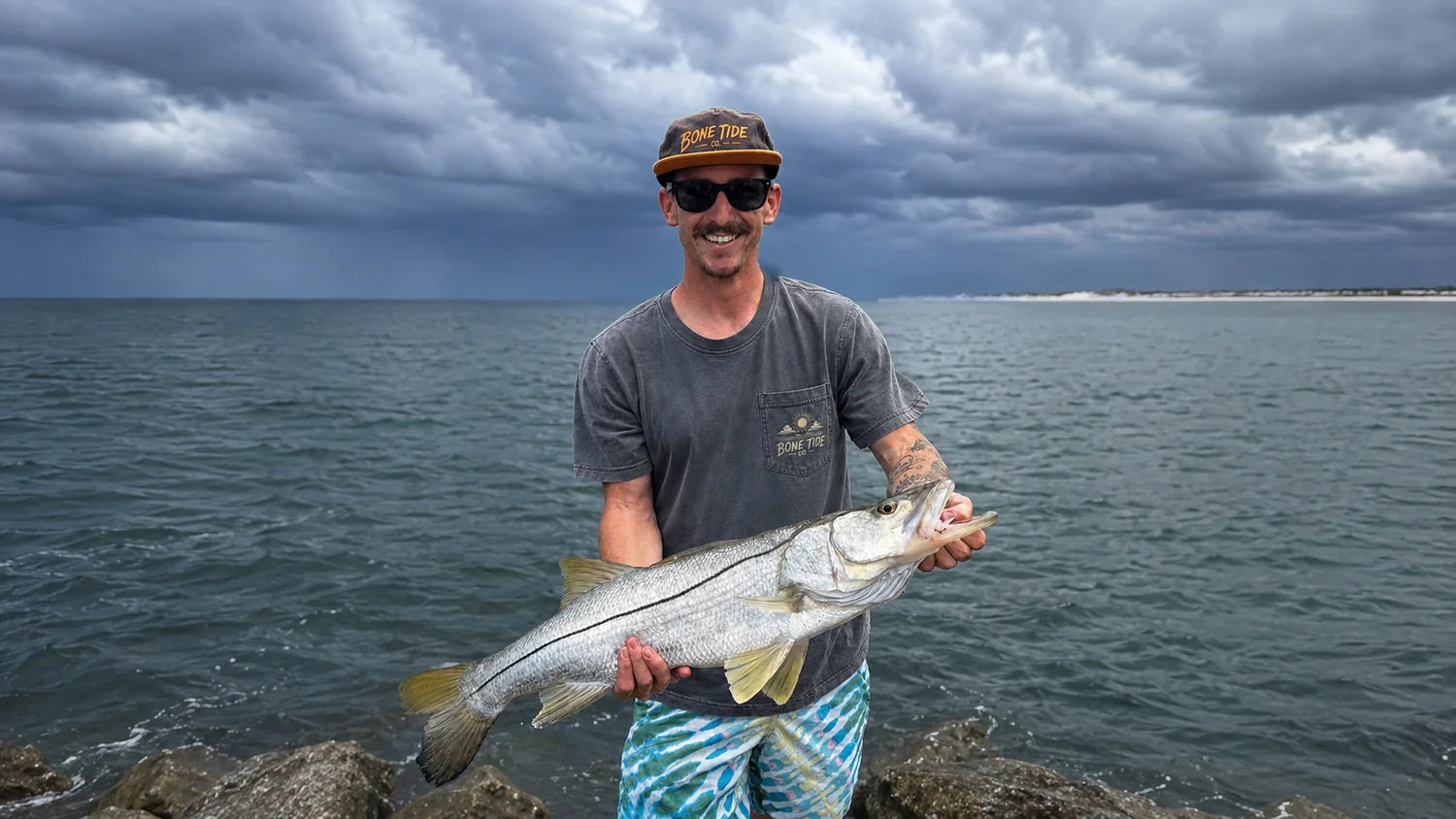 Angler in Bone Tide Co. gear holding a snook